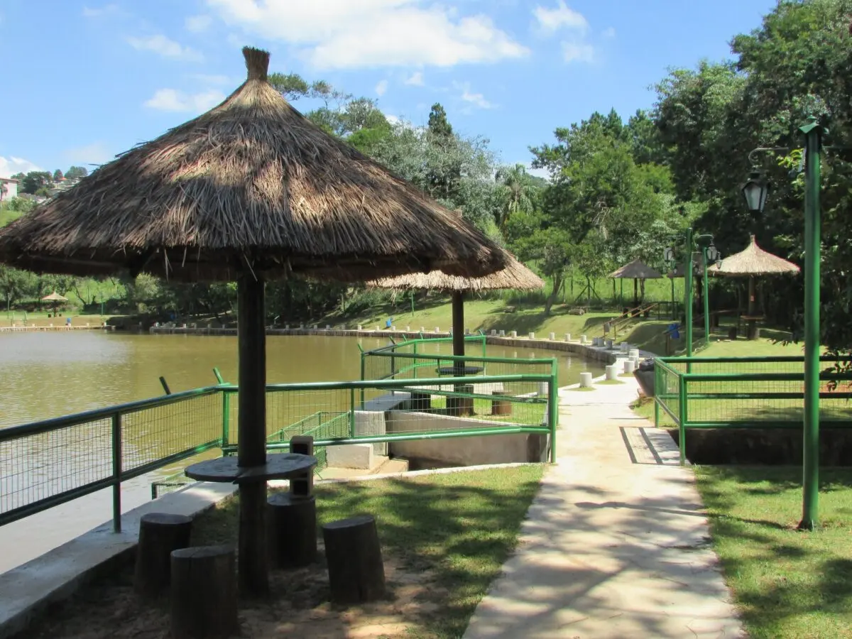 Quiosques de sapê e mesas à beira do lago do Pesqueiro Recanto Maravilha, em Santana de Parnaíba