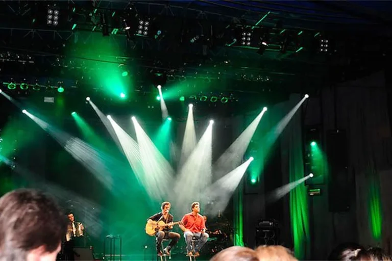 Palco iluminado com luzes verdes durante show ao ar livre