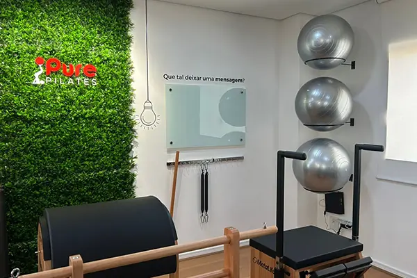 Aparelhos de Pilates e parede com a marca na unidade Centro de Santana de Parnaíba.