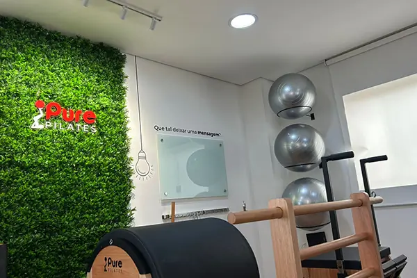 Parede com a marca e equipamentos na Pure Pilates Centro.